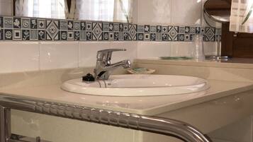 Un baño con lavamanos blanco, grifo cromado y salpicadero de azulejos.