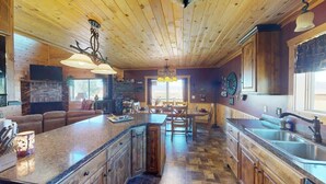 Une cuisine spacieuse dotée d’un grand îlot central, de meubles en bois et d’une cheminée en pierre.