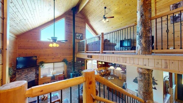 Une cabane en bois à plusieurs niveaux, dotée d’un téléviseur, d’un coin repas et d’un escalier.