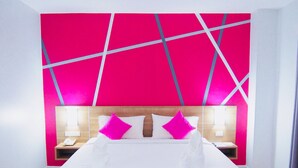 Une chambre d’hôtel moderne avec un grand lit, un mur d’accent de couleur rose vif et une tête de lit en bois.