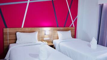 A hotel room with two beds, a wooden headboard, a wall with geometric patterns, and a nightstand with a phone.