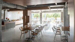 Un vaste espace de restauration intérieur, doté de hauts plafonds et de grandes fenêtres, et aménagé avec un mélange de meubles en bois et en métal.