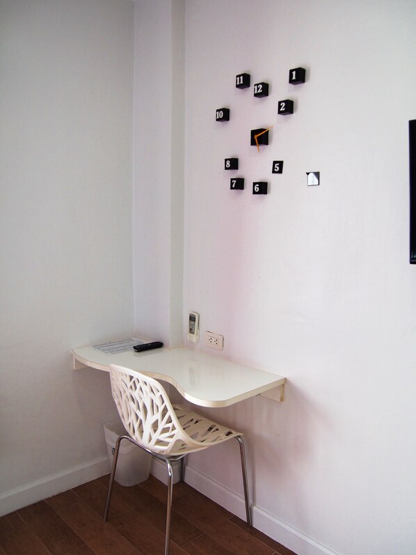 A small, white desk with a white chair in a corner of a room with white walls. - Eco Inn Lite Ubon Ratchathani (Ubon Ratchathani)
