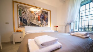 Una habitación de hotel con una cama grande, una mesita de noche con un jarrón de flores y un cuadro en la pared.