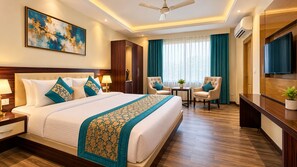 A hotel room with a large bed, two armchairs, a small table, and a TV. - Hotel Banz (New Delhi)