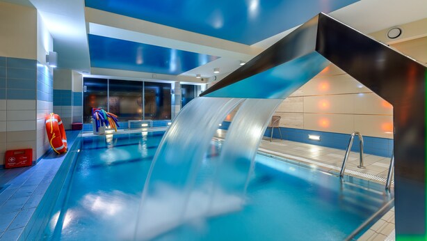 A modern indoor swimming pool with a water slide, clear pool edges, and a lifeguard stand. - Perelka Kolobrzeg (Kolobrzeg)