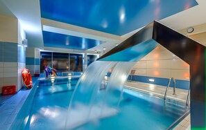 Une piscine intérieure moderne dotée d’un toboggan, de bords bien définis et d’un poste de surveillance pour les sauveteurs.