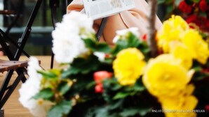 A person sitting at a table with a magazine, a cup, and a glass of water. - Perelka Kolobrzeg (Kolobrzeg)