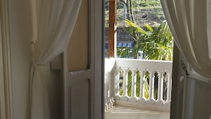Een kamer met uitzicht op een balkon, een witte vaas en een betegelde vloer.