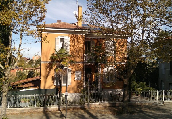 A two-story building with a balcony, surrounded by trees and a fence. - Villa Liberty Urbino (Urbino)