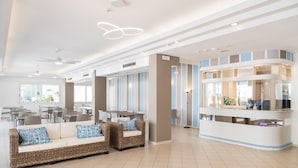 A modern hotel lobby with a reception desk, seating area, and dining space. - Hotel Amalfi riccione (Riccione)