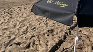 A beach with a black umbrella labeled "El Camino apart" and footprints in the sand. - El Horreo Apart (Villa Gesell)