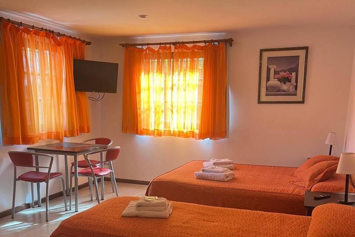 Quarto com duas camas, uma escrivaninha e uma cadeira.