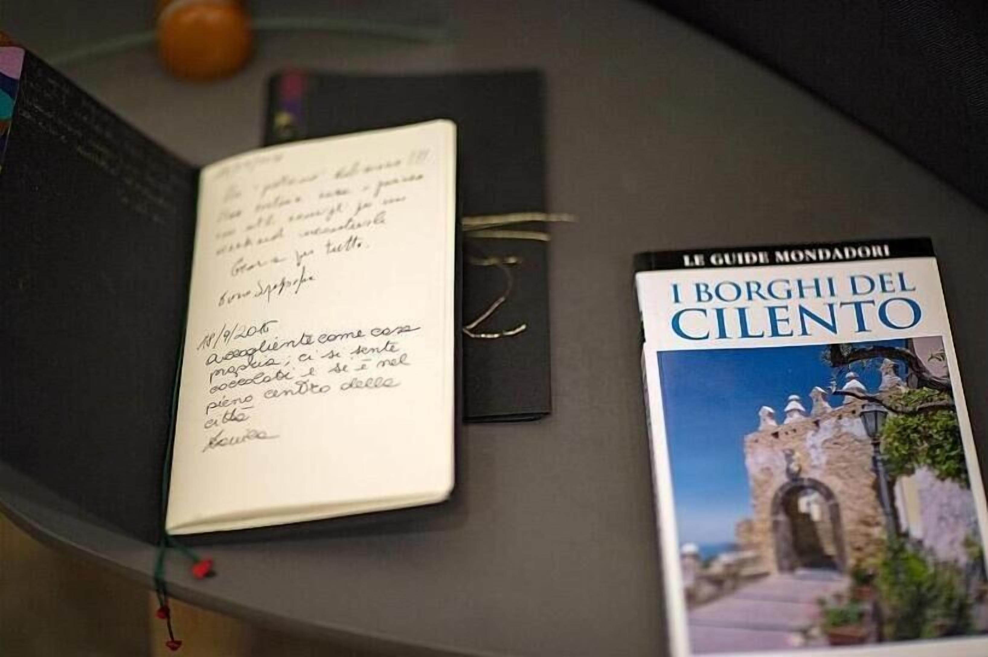 A notebook with handwritten notes and a book titled 'I Borghi del Cilento' on a table.
