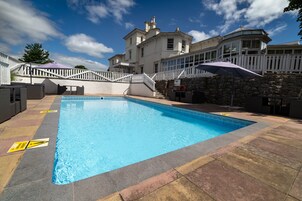 Una piscina al aire libre de temporada, sombrillas