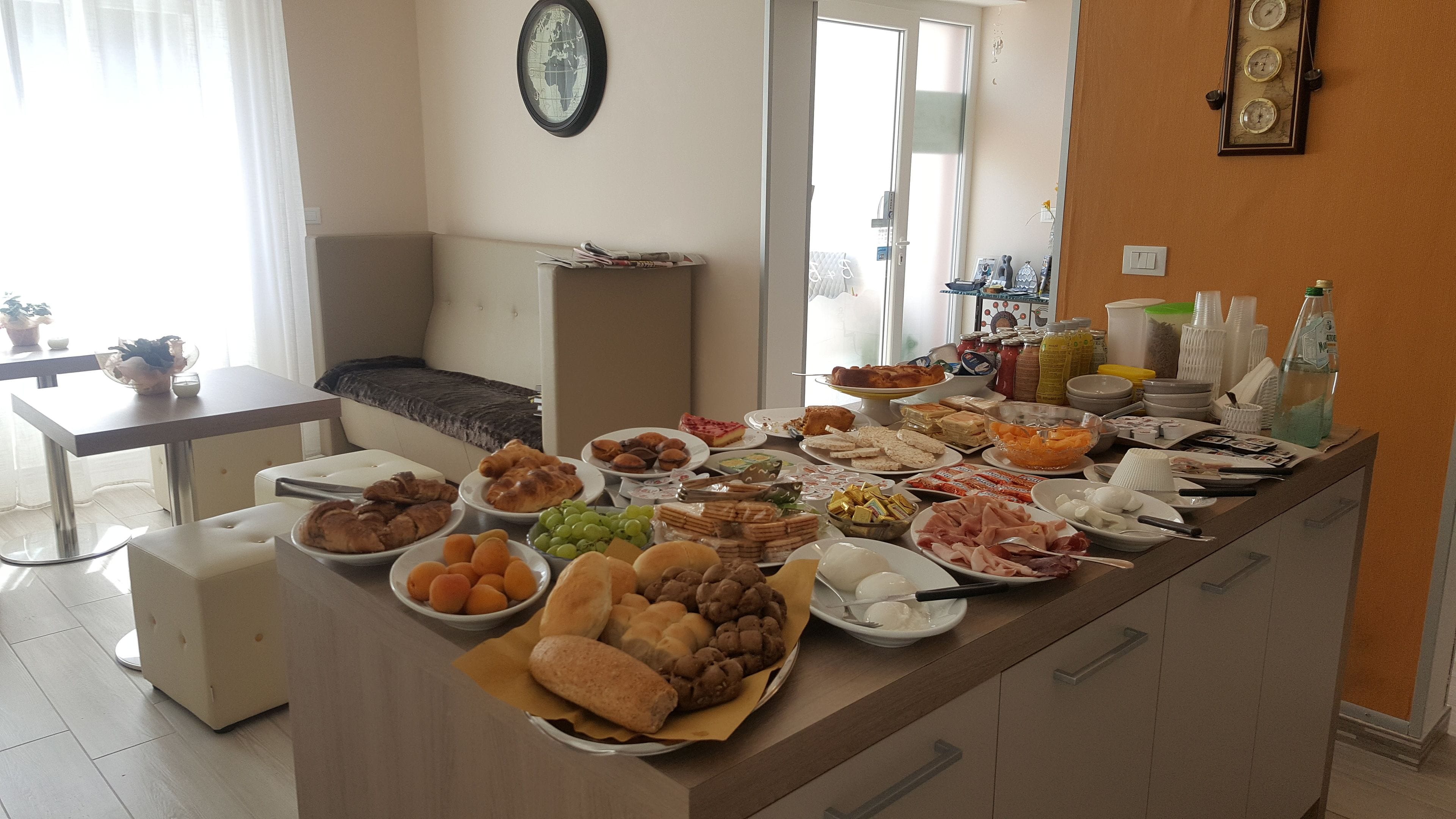 A buffet table with various food items and a seating area with a sofa and a dining table.