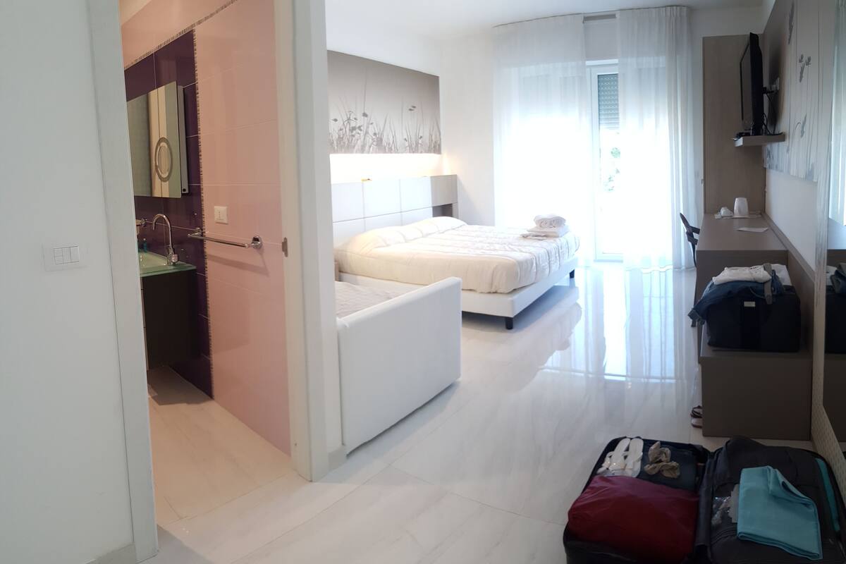 A hotel room with a bed, a desk, and a bathroom.