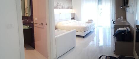 A hotel room with a bed, a desk, and a bathroom.