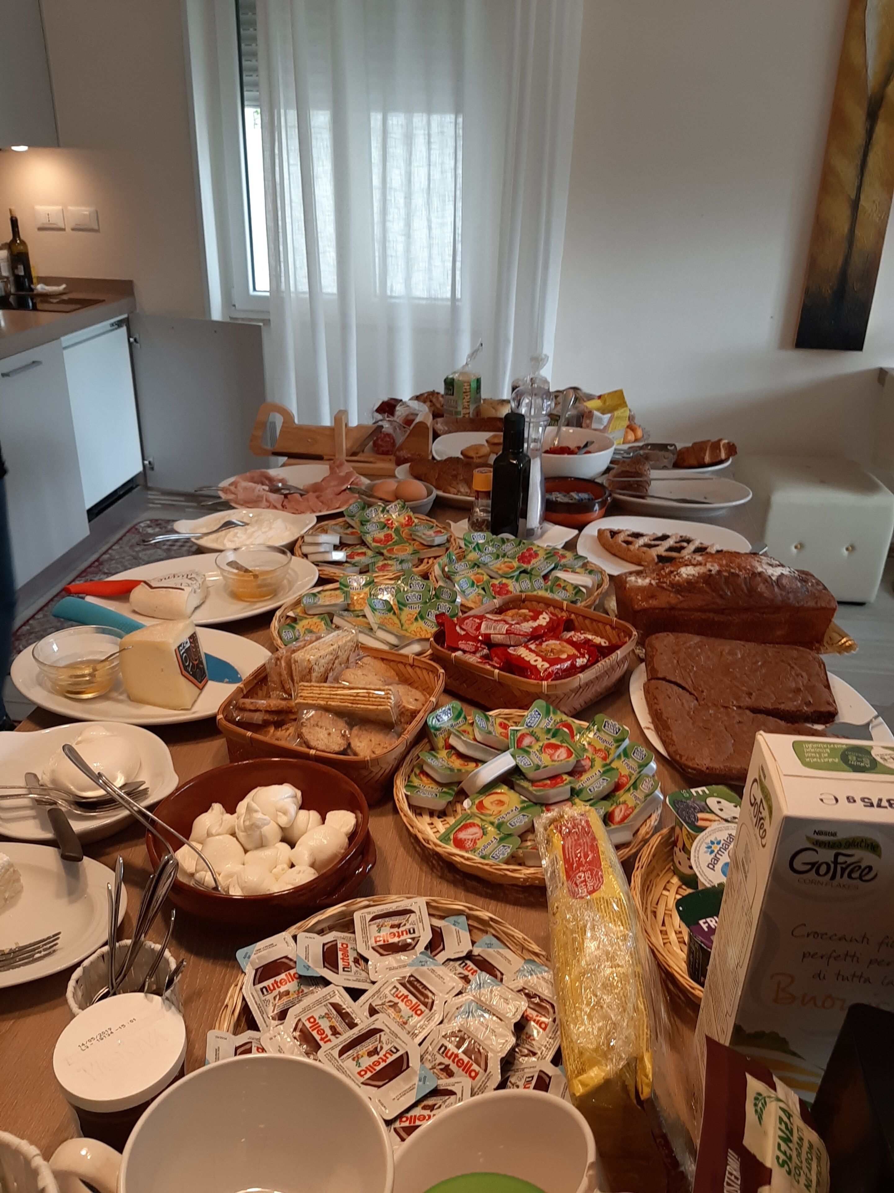 A dining table with various food items and condiments, including bread, cheese, and packaged snacks.