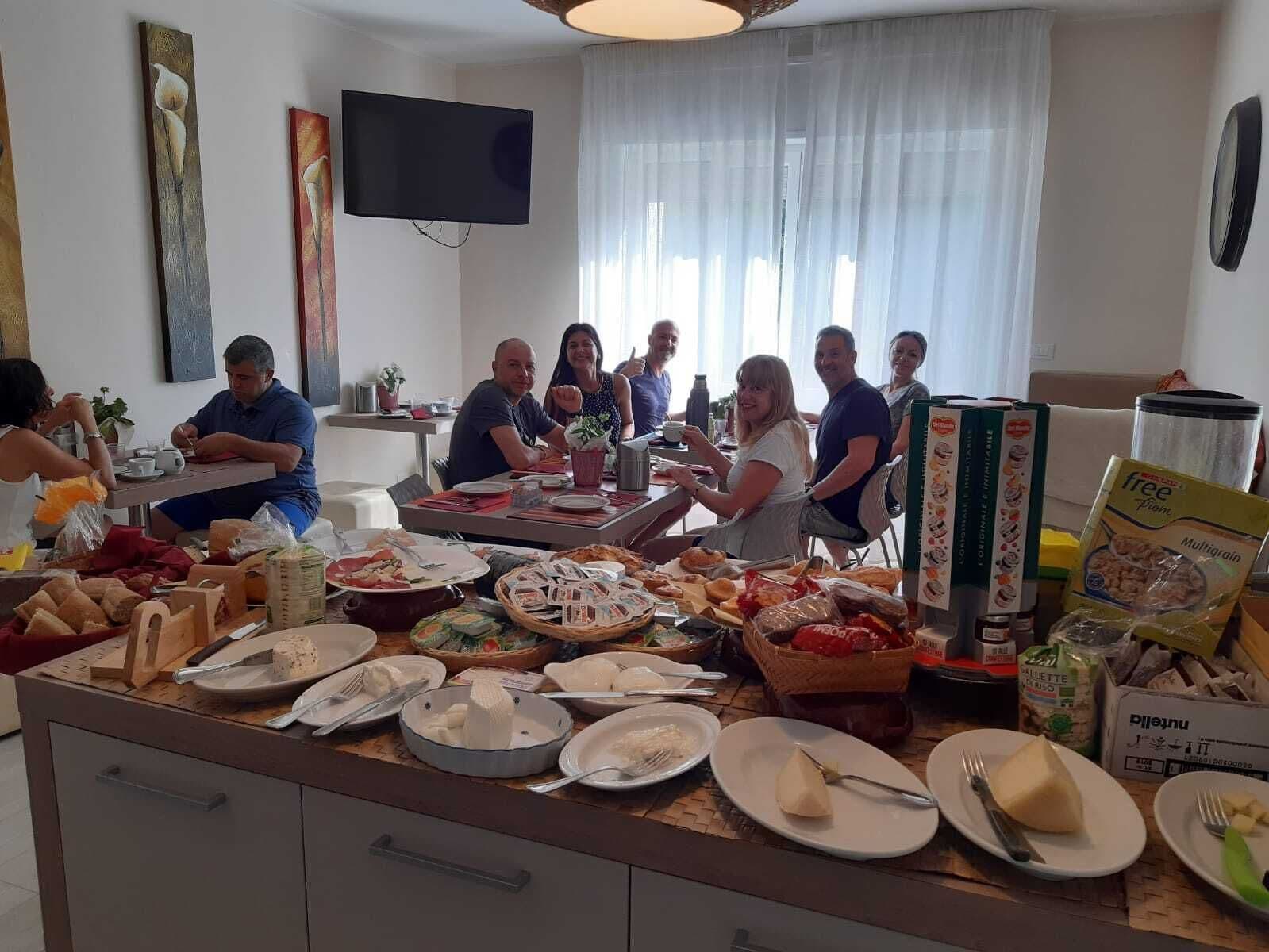 Un comedor común con mesas de buffet, un televisor de pantalla plana en la pared y un grupo de personas sentadas alrededor de una mesa.