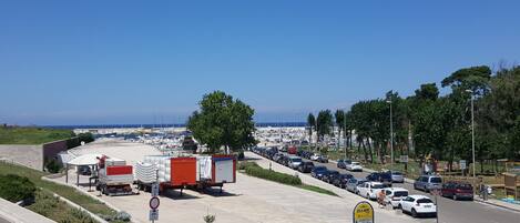 A parking lot with a view of a marina and boats in the background.