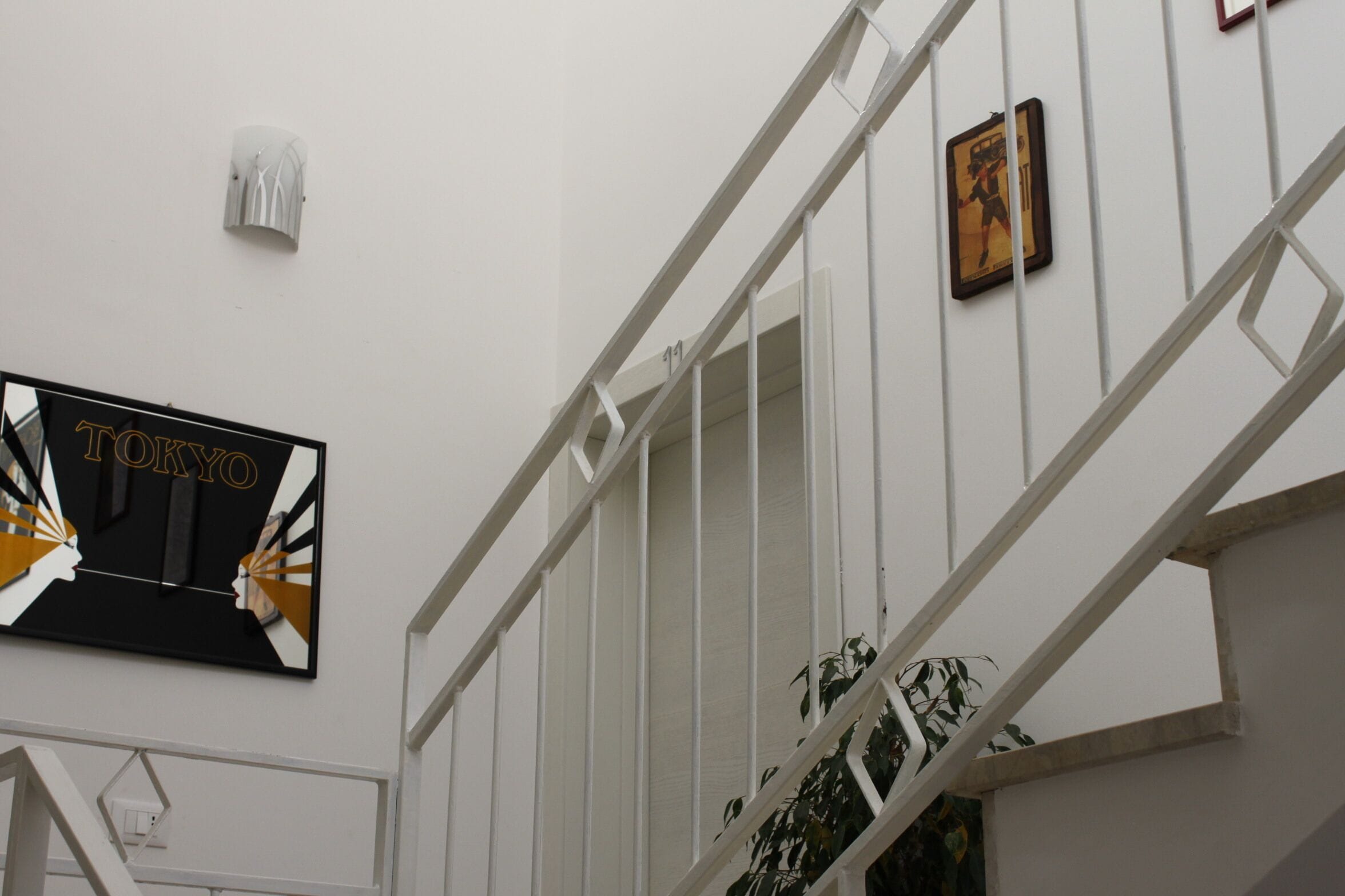 A staircase with white railings and a wall-mounted sign that reads "TOKYO".