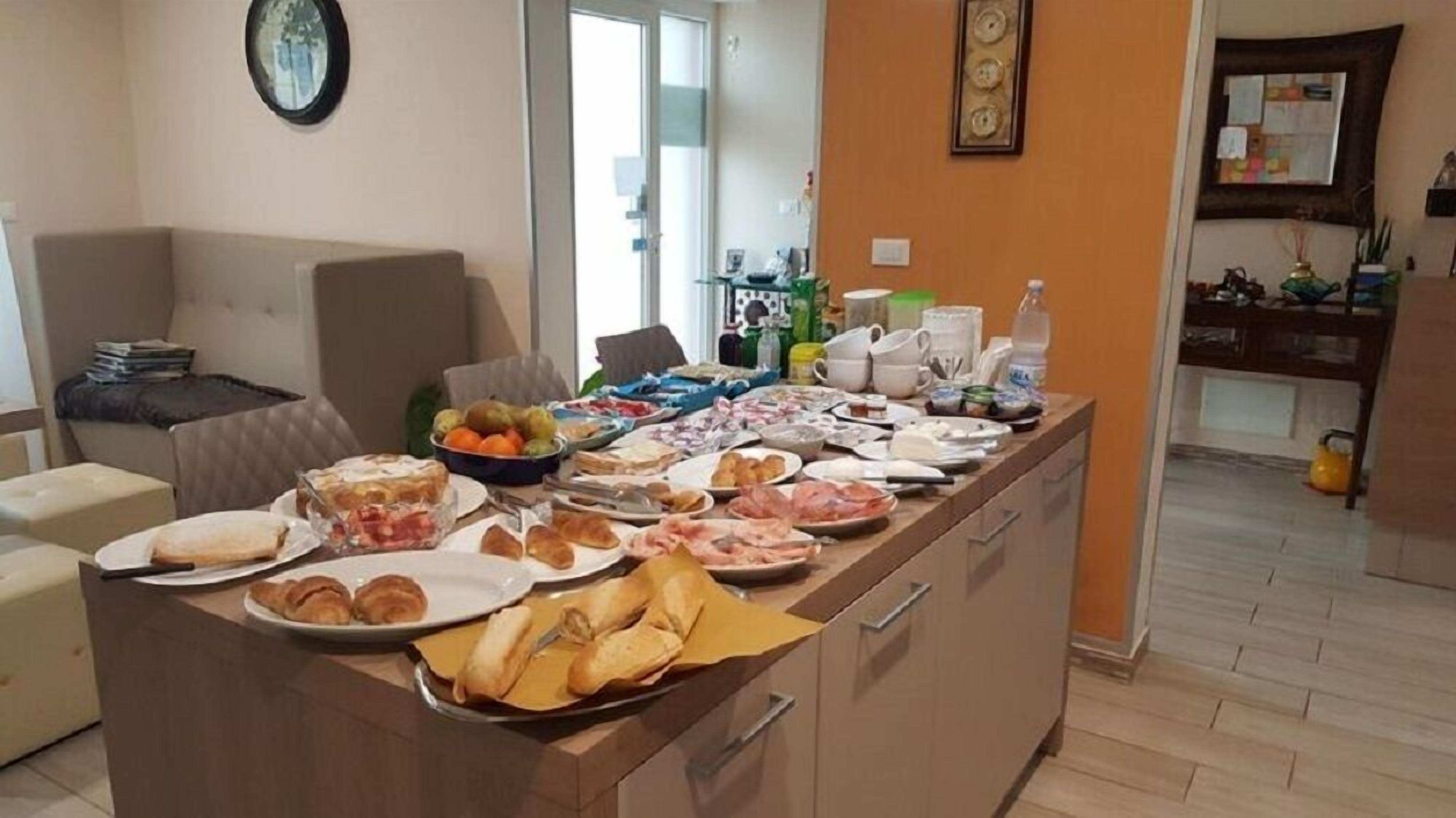 A kitchen area with a buffet setup featuring various food items and a dining area with a sofa and a coffee table.