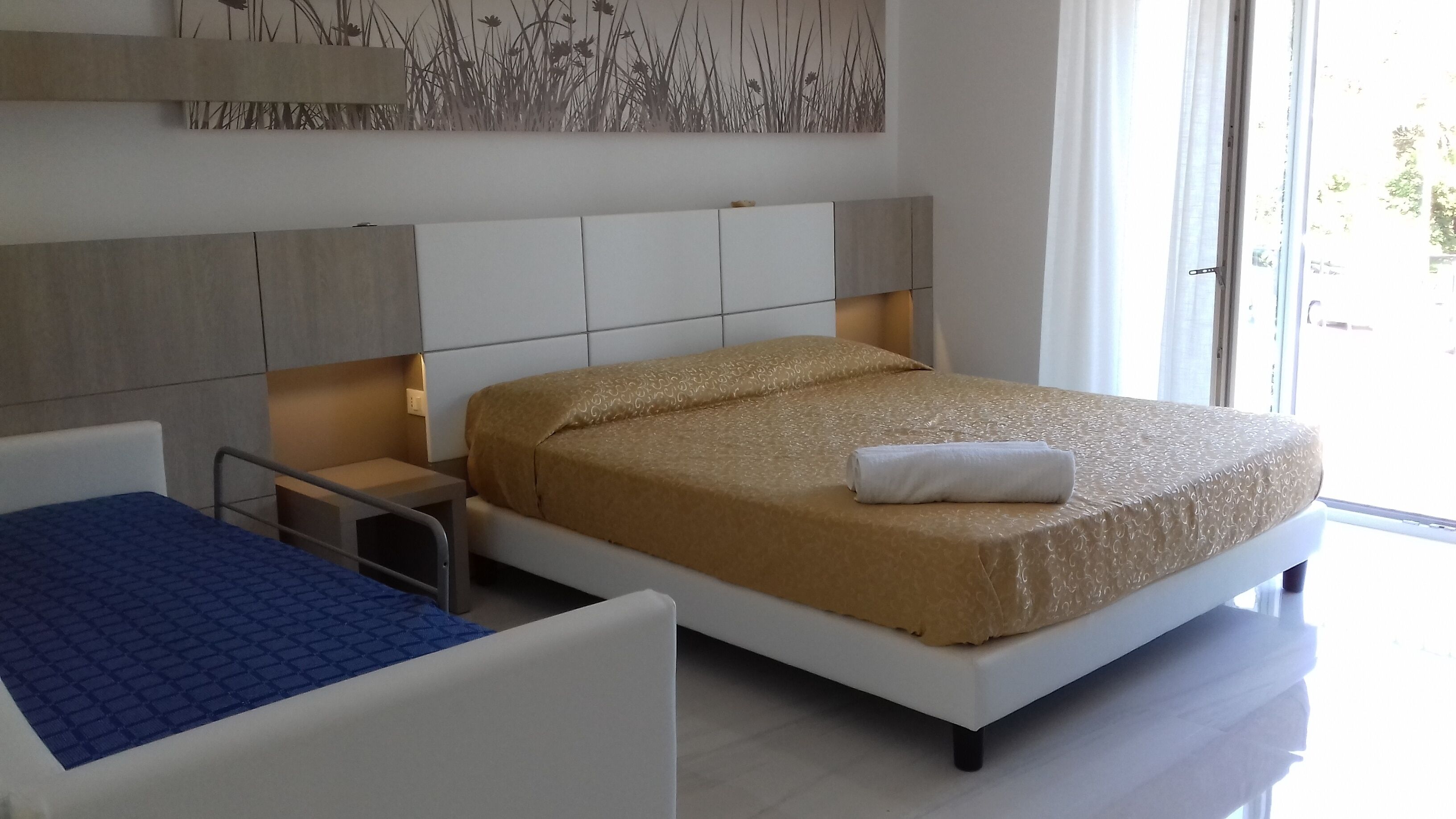 A modern hotel room with a large bed, a bedside table, and a small desk.