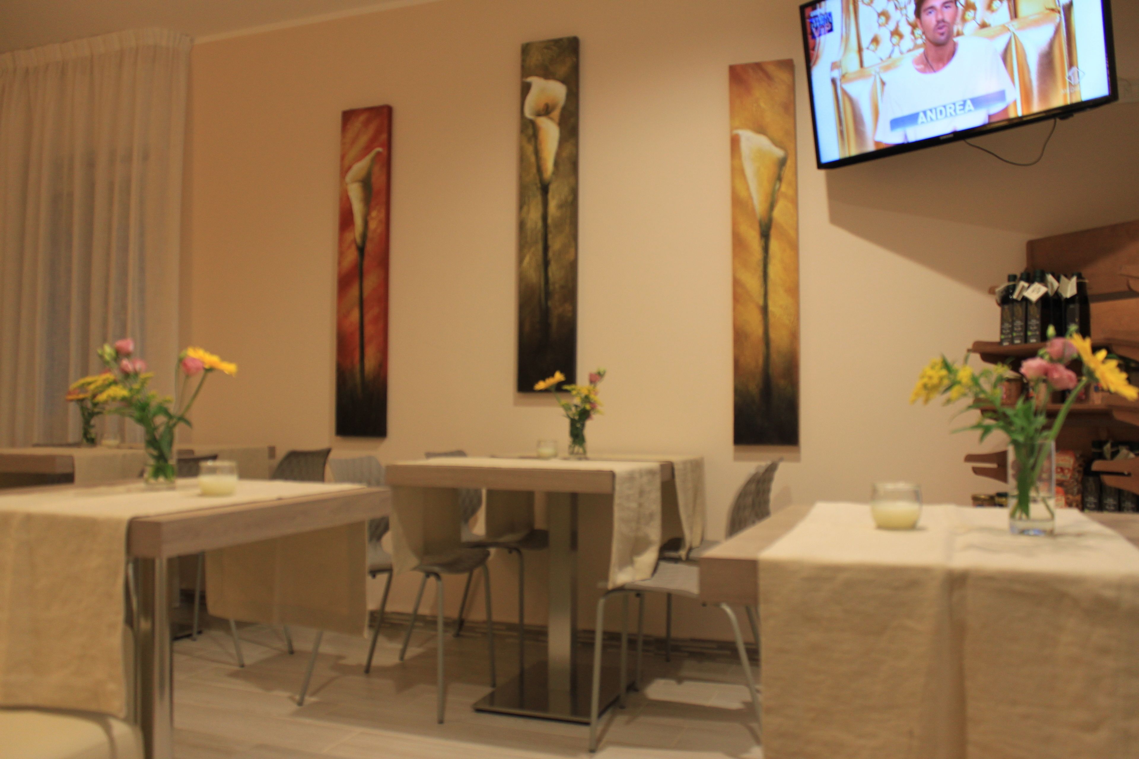 A dining area with tables, chairs, and artwork on the walls.