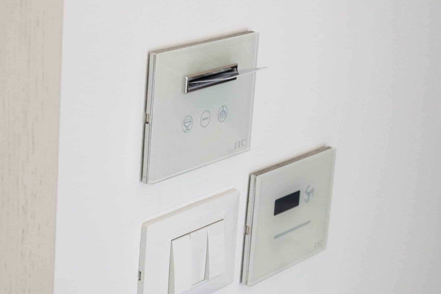 Three switches on a wall, one with a pen in it, and two blank switches.