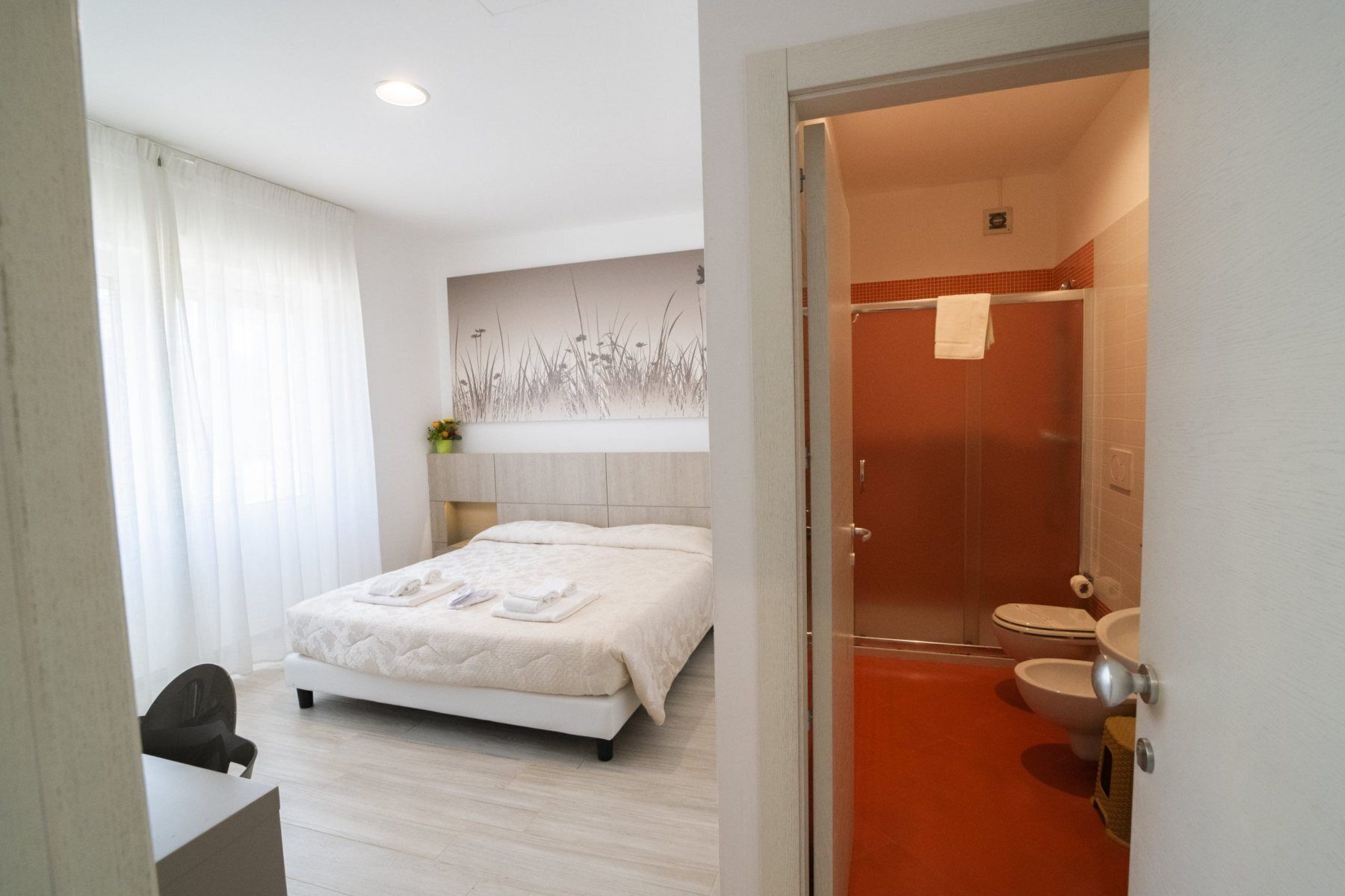 Una habitación de hotel con cama, escritorio, ducha y baño.