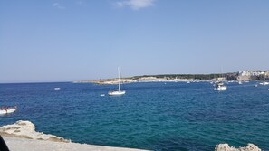 Vista costera con barcos en el agua y un litoral rocoso.
