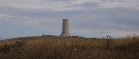 Un monumento solitario sobre una colina cubierta de hierba, bajo un cielo nublado.