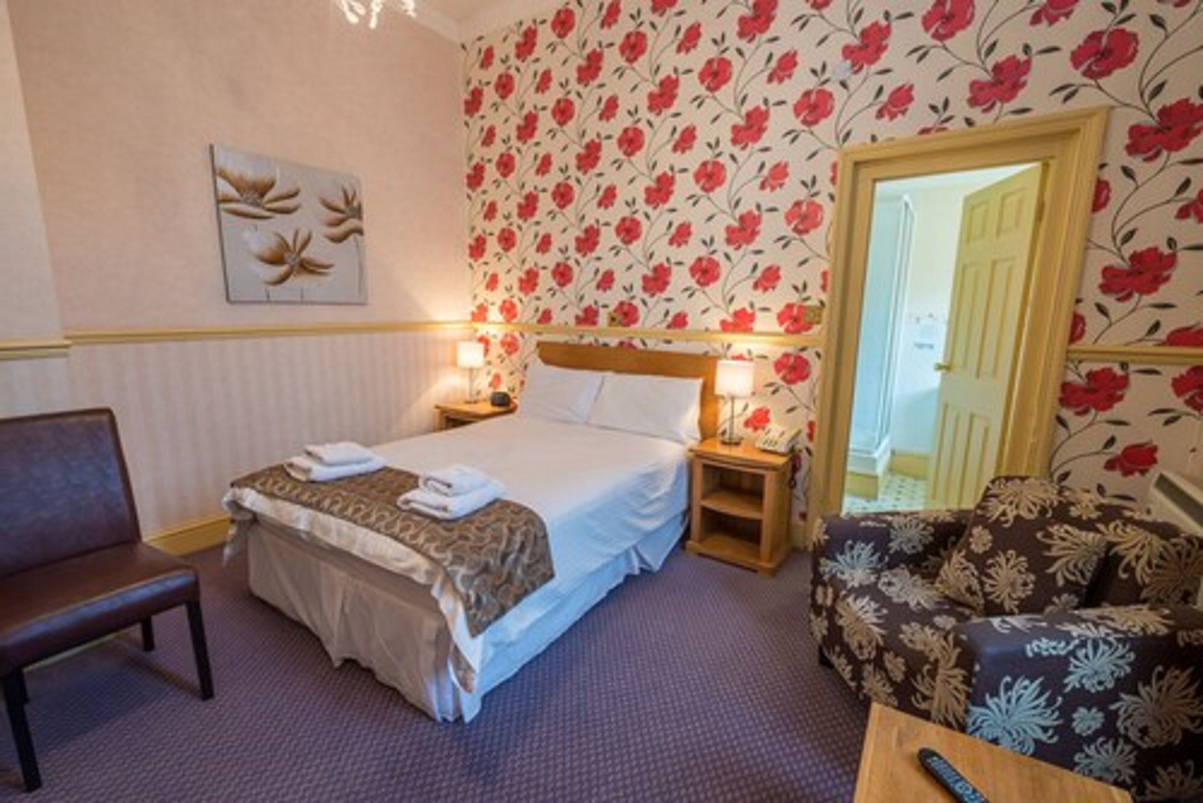 A hotel room with a bed, bedside tables, a chair, and a sofa.
