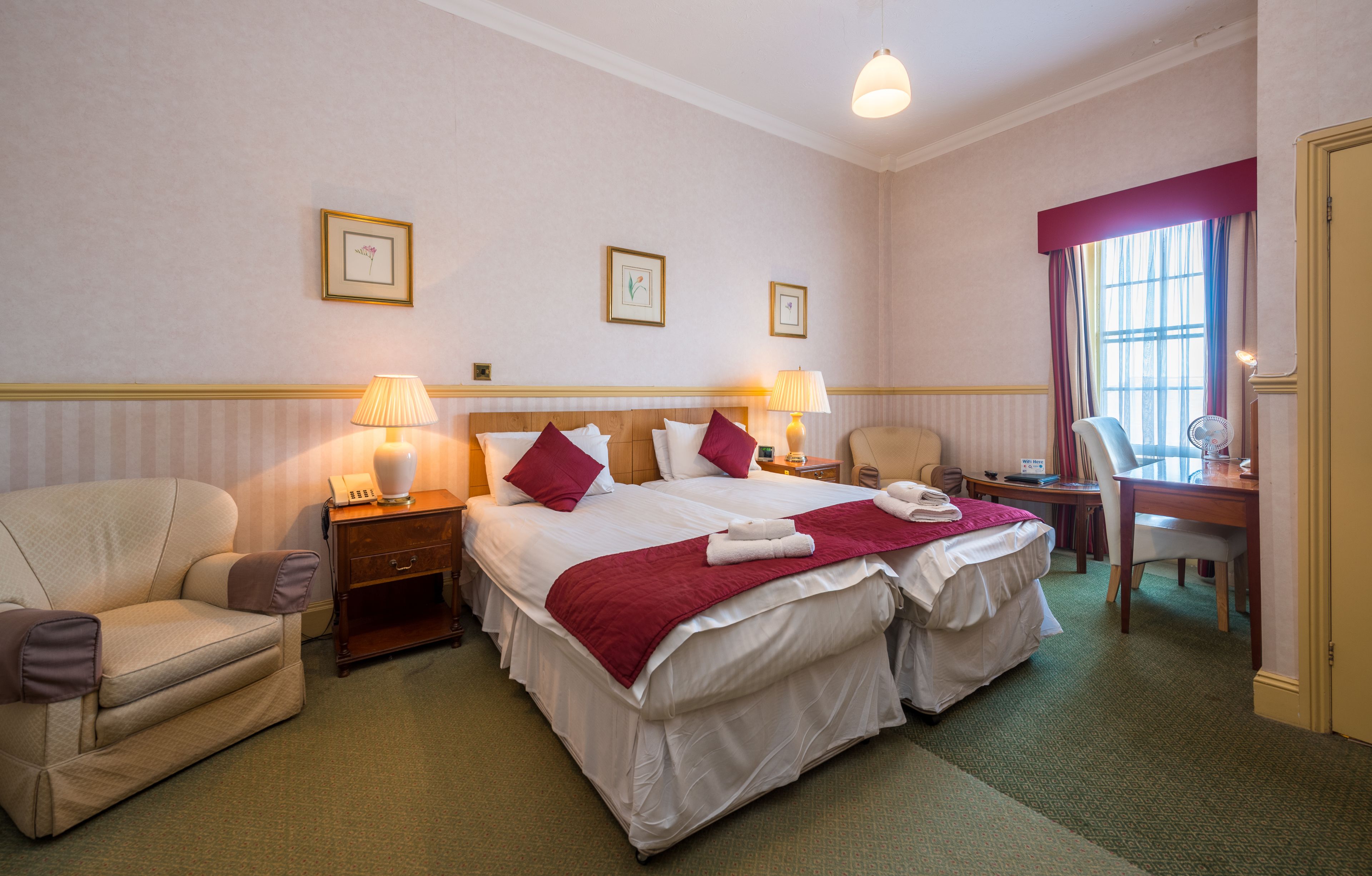 A hotel room with two beds, a desk, a chair, and a sofa.