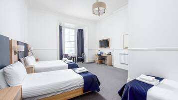 Habitación de hotel con dos camas, un escritorio, una silla, un televisor y una ventana con cortinas.