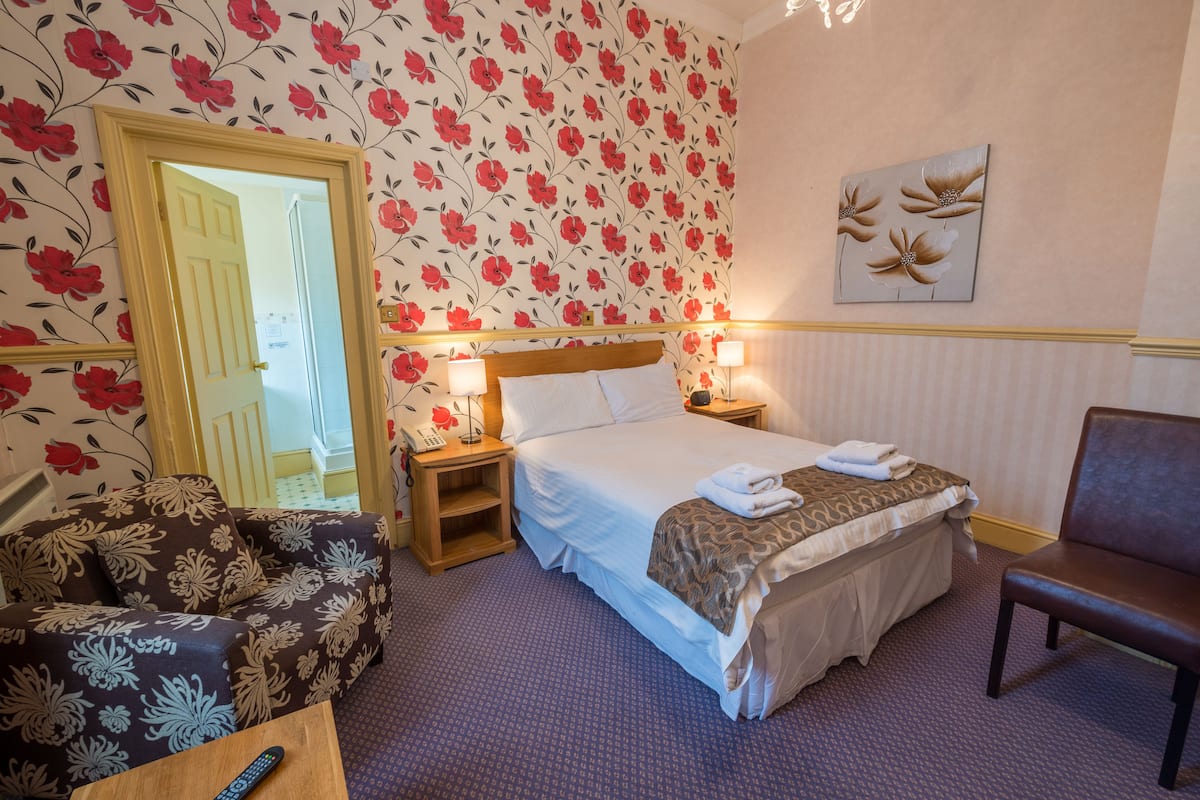 A hotel room with a bed, bedside tables, a chair, and a sofa.