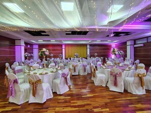 A banquet hall with round tables, white tablecloths, and chairs with gold sashes.