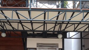 Un edificio de varios niveles con ascensor central, barandales de metal y una escalera.