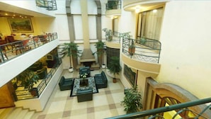 Un vestíbulo de hotel con piso a cuadros, chimenea y varios balcones.