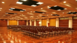 Un amplio salón de conferencias con filas de sillas, un atril y un escenario.