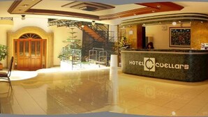 Zona de recepción de un hotel con mostrador, escalera y un amplio ventanal.