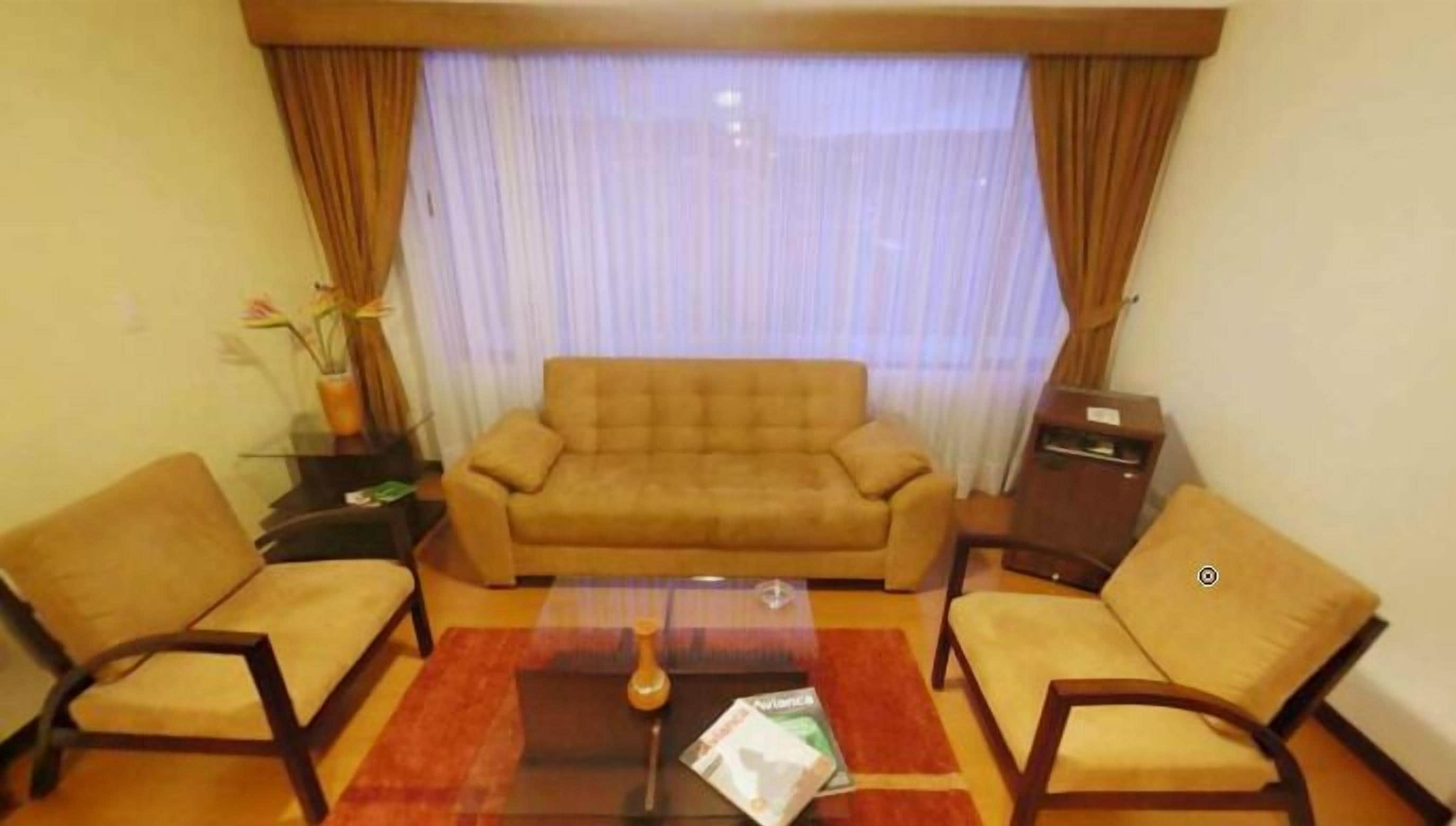 Una sala de estar con sofá, dos sillones, una mesa de centro y un mueble para televisión.