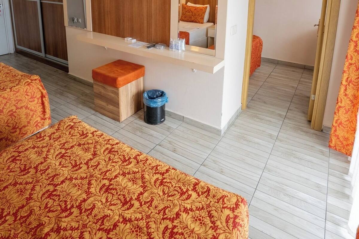 A hotel room with a large bed, a wooden headboard, a TV mounted on the wall, a mirror, and a small table.