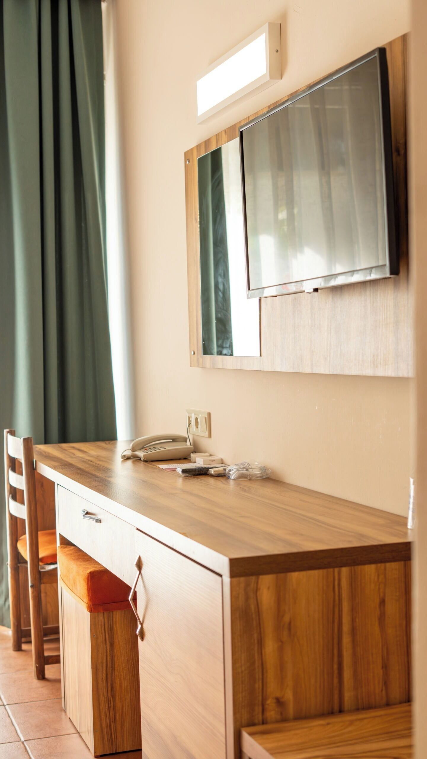 Un comptoir en bois avec un téléphone, un miroir et un petit placard.