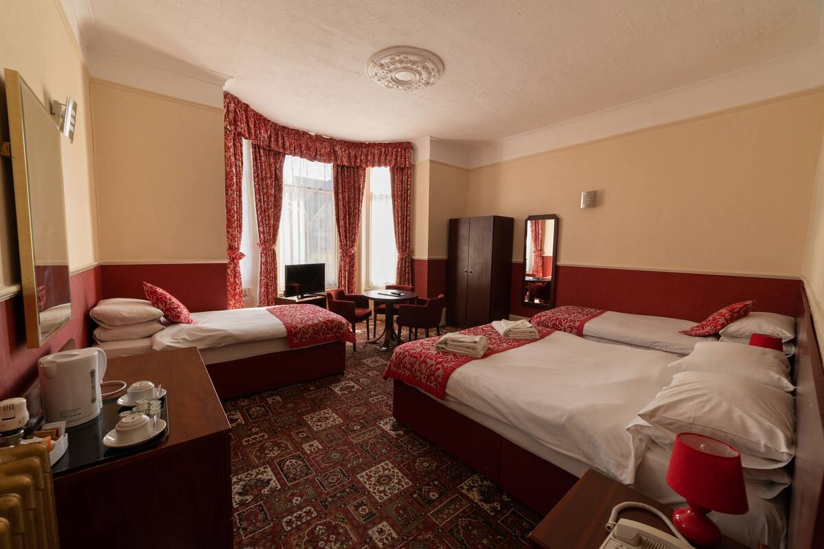 A hotel room with two beds, a desk, a chair, a television, and a wardrobe.