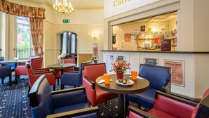 A coffee shop with red and blue seating, a chandelier, and a sign indicating the coffee shop.