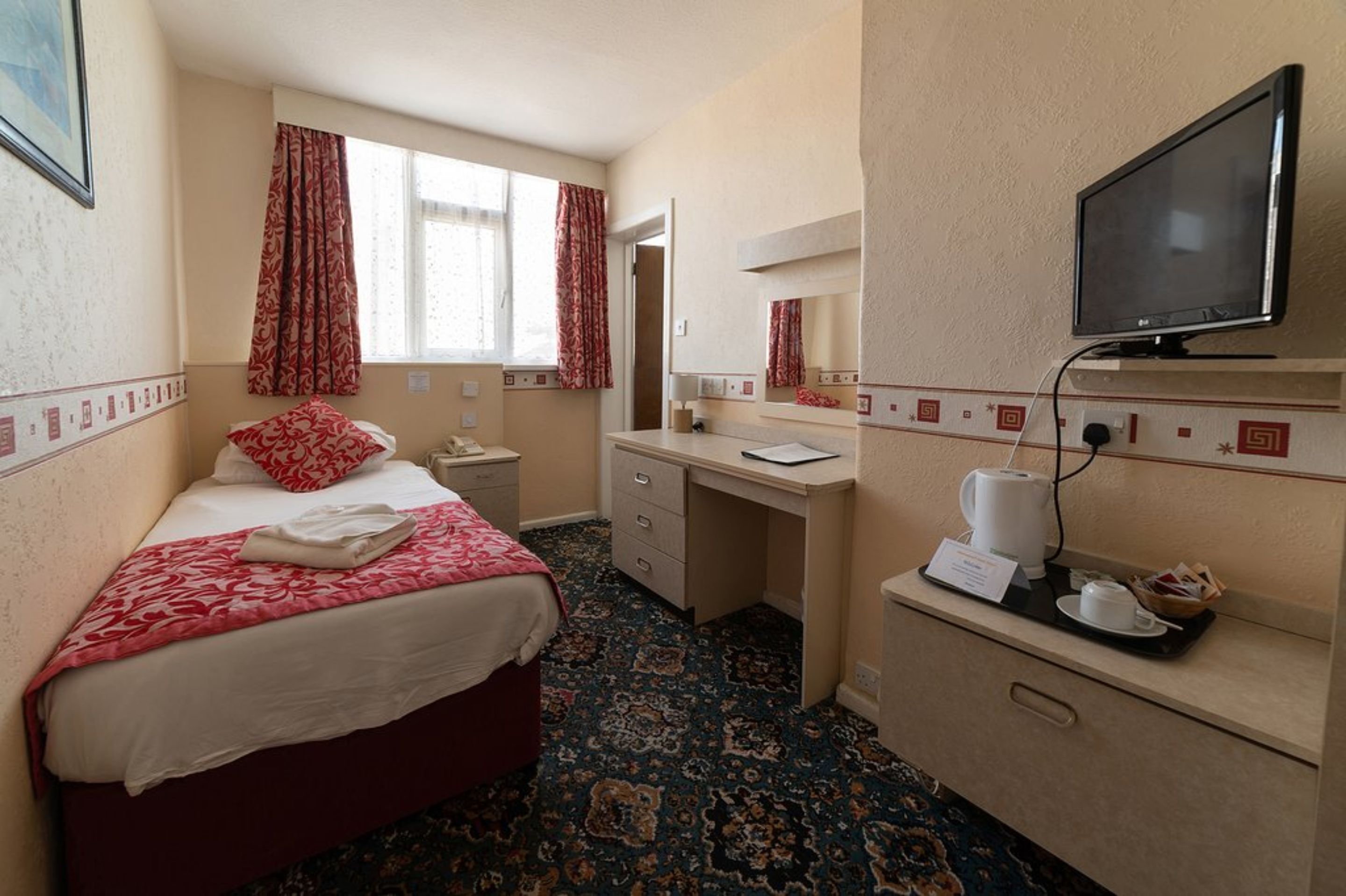 A hotel room with a bed, a desk, a television, and a coffee maker.
