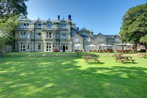 A large stone building with multiple windows and a lawn area with picnic tables. - Daish's Hotel (Shanklin)