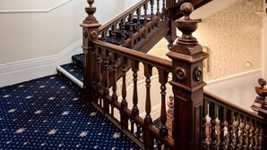A grand staircase with ornate wood railings and a patterned carpet.
